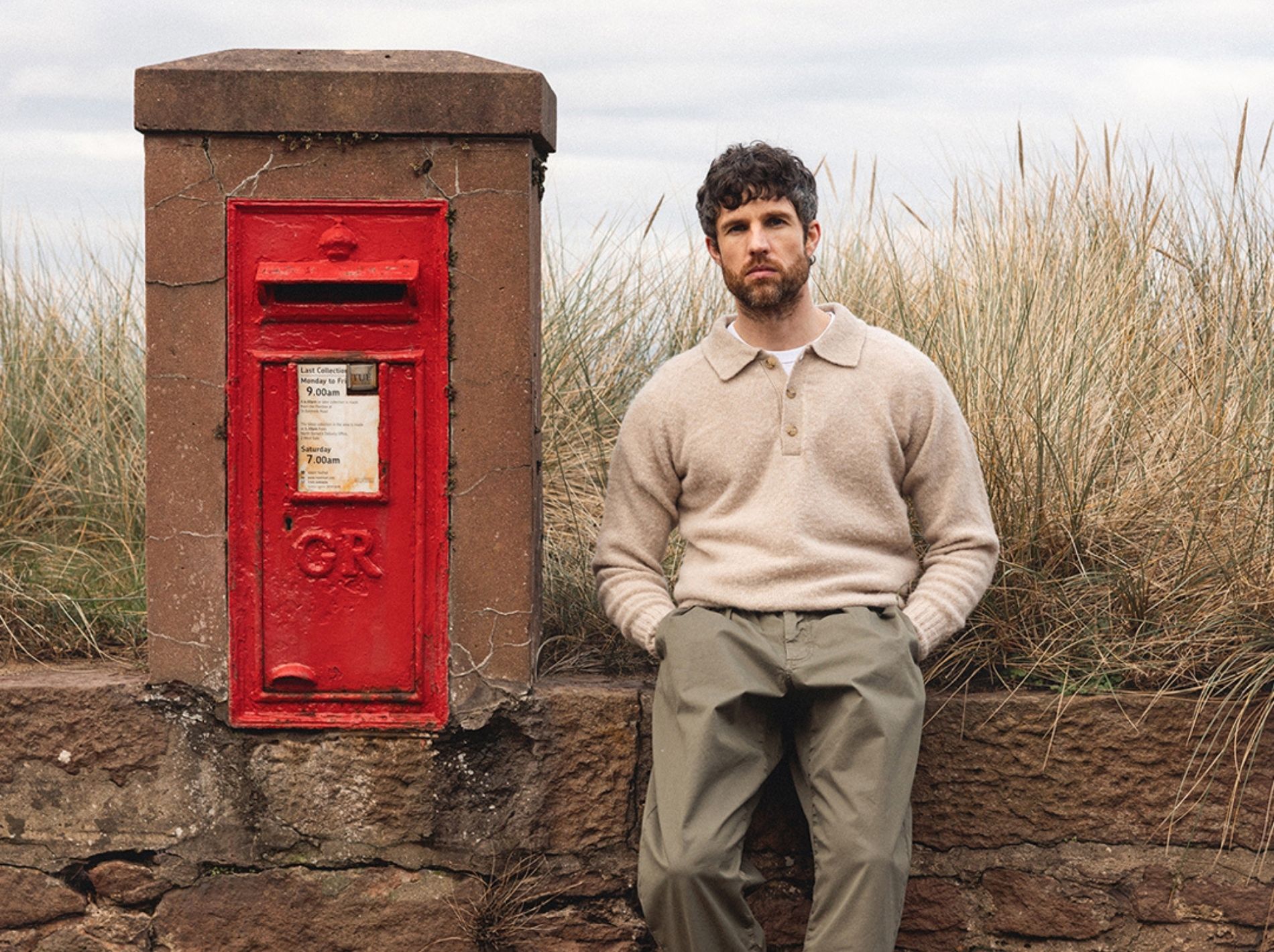 model shot of man leaning against wall wearing kestin knitwear